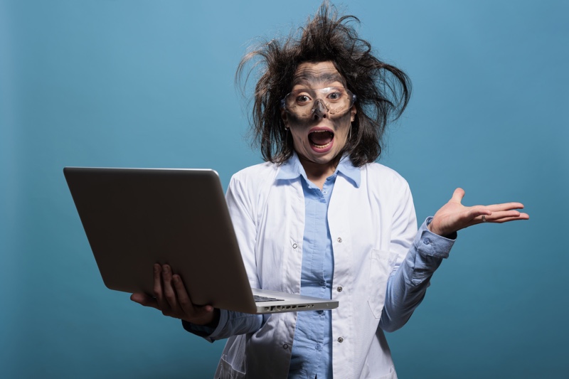 Crazy panicked scientist screaming in panic after laboratory explosion while having laptop.